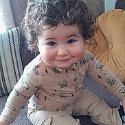 Joud a rejoint le concours — aidez-le/la à gagner de superbes lots ! toddler, child, curly_hair, smiling, sitting, couch, pillow, beige_pants, bear_print, long_sleeve_shirt, indoor, cozy, happy, cute, face, person, clothing, home, young_child, portrait