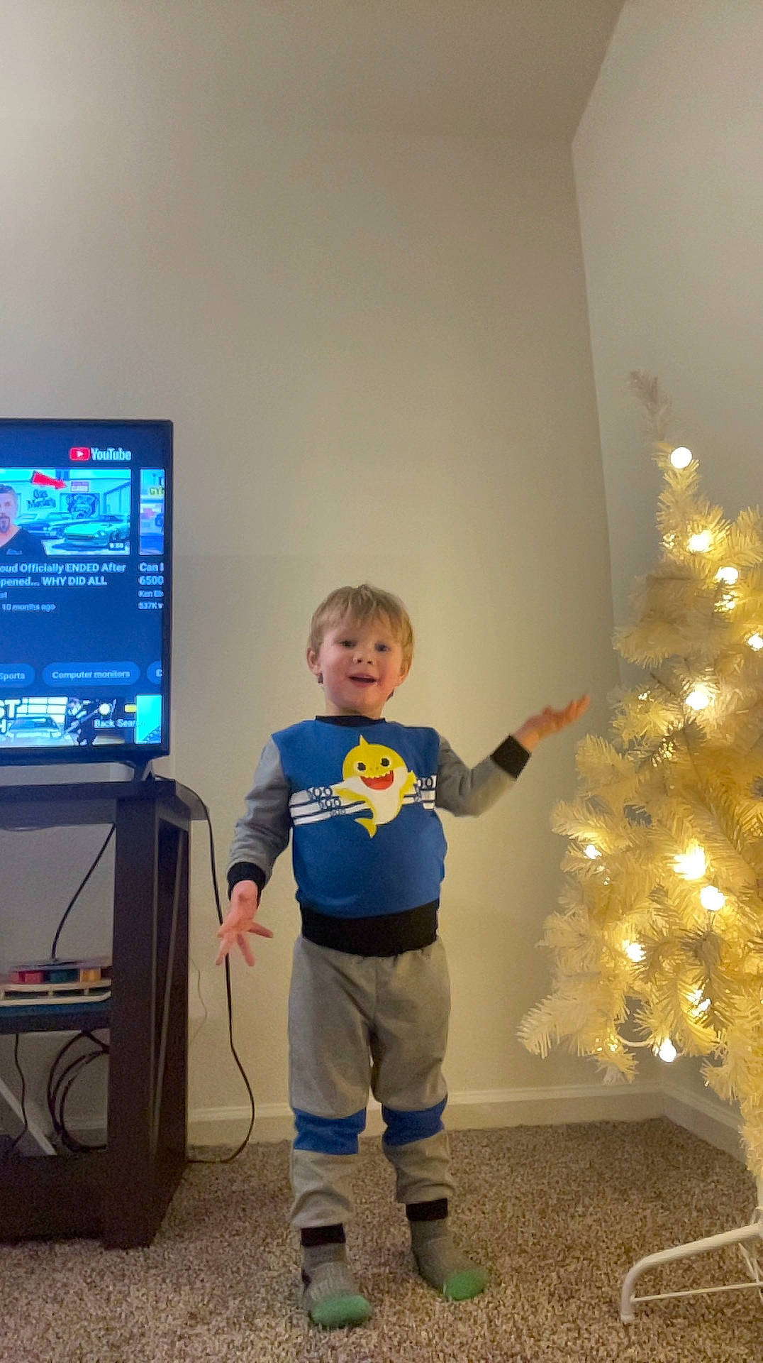 Christopher is registered to the contest to win money with this photo: child, christmas_ornament, christmas_tree, display_device, electric_blue, event, flooring, fun, gadget, holiday_ornament, home_appliance, machine, ornament, person, room, standing, t_shirt, television, television_set, toddler