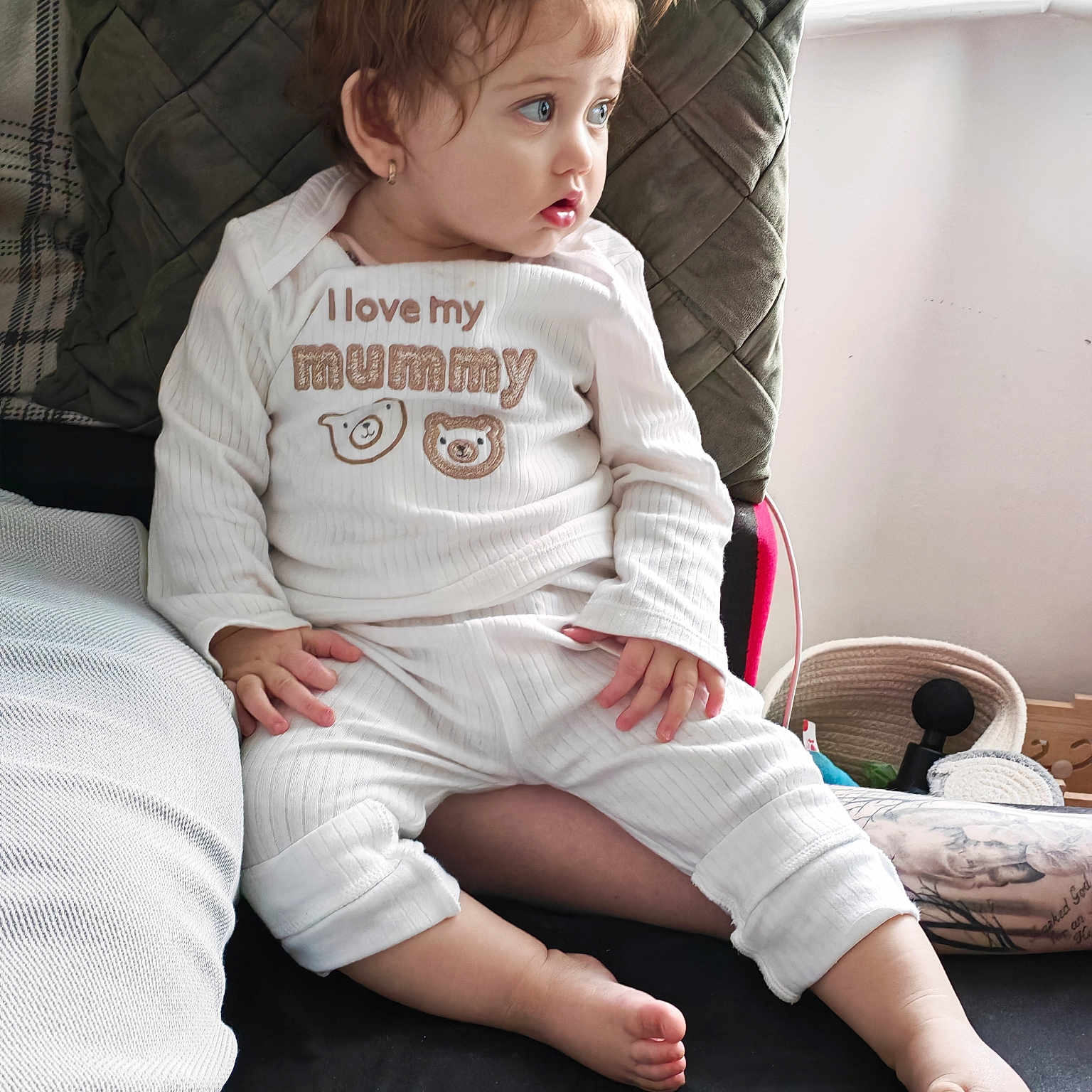 Georgiana is registered to the contest to win money with this photo: barefoot, child, comfort, couch, cozy, curly_hair, cushion, cute, expression, face, home, indoor, looking_away, pajamas, pony_tail, sitting, small_hands, toddler, white_clothing, young_child