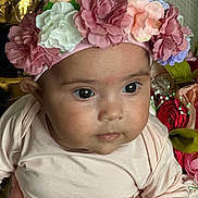 Amélie participe au concours pour gagner de l'argent avec cette photo : baby, flower_headband, pink_clothing, close_up, hand, face, eyes, infant, portrait, curious, skin, artificial_flowers, floral, background, person, child, cute, soft_lighting, indoors, head