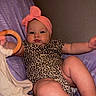 baby, infant, child, leopard_print, headwrap, pink, toy, wooden_ring, blanket, purple, pout, chubby_cheeks, onesie, indoor, portrait, cute, relaxed, reclining, person, young