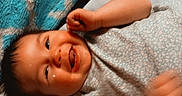 Noelle joined the competition — help win amazing prizes! baby, infant, child, smiling, laughing, lying_down, bed, blanket, pillow, bedding, portrait, face, eyes, hands, fist, onesie, indoors, cozy, happy, date_stamp