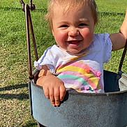 Noelle is registered to the contest to win money with this photo: toddler, child, baby, smiling, happy, swing, playground, outdoor, grass, sunlight, portrait, face, person, park, fence, bench, pool, summer, clothing, rainbow