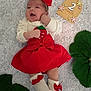 Elodie is registered to the contest to win money with this photo: baby, infant, red_bow, red_skirt, white_sweater, milestone_sign, flower_decorations, green_leaves, blanket, cute, lying_down, headband, socks, baby_clothes, portrait, smiling, two_months, child, soft_texture, indoors