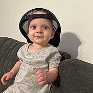 Kinsley joined the competition — help win amazing prizes! baby, babylaughing, bodypart, clothing, couch, dress, face, finger, furniture, hand, happy, hat, head, helmet, person, photography, portrait, sitting, sleeve, smile