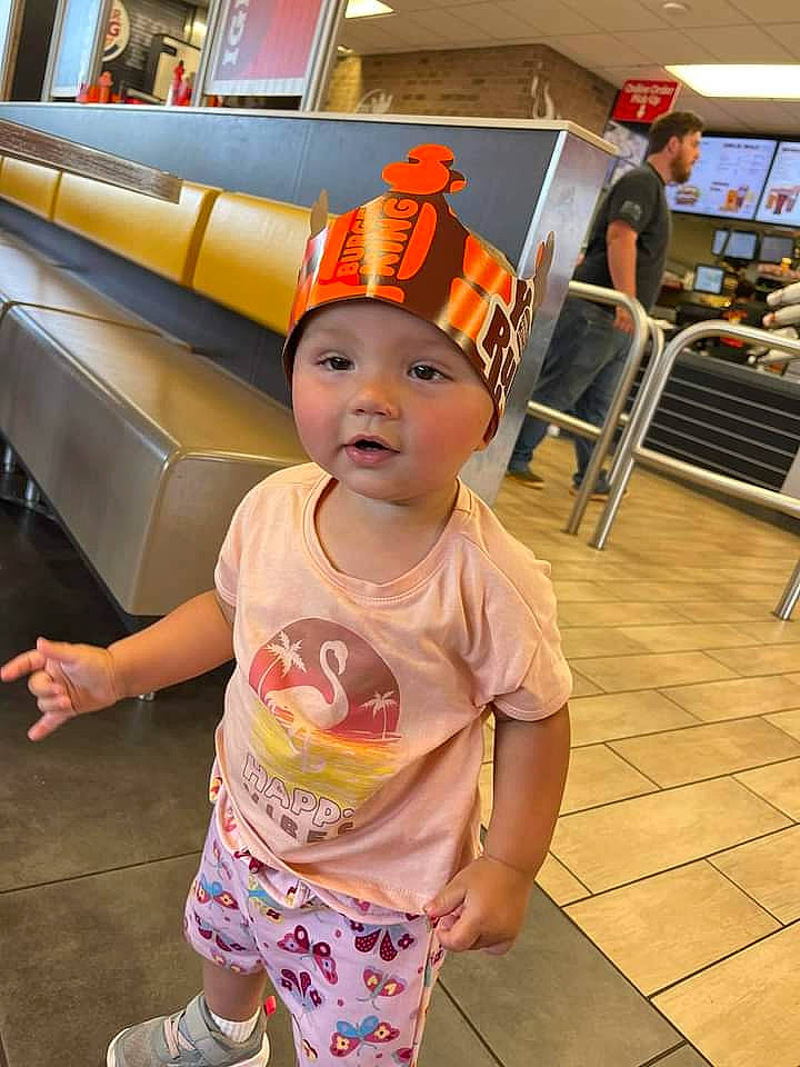 Aubree is registered to the contest to win money with this photo: baby, baby_toddler_clothing, baseball_cap, cap, chair, child, costume, costume_hat, fashion_accessory, flooring, foot, fun, happy, hat, headwear, orange, person, room, service, t_shirt
