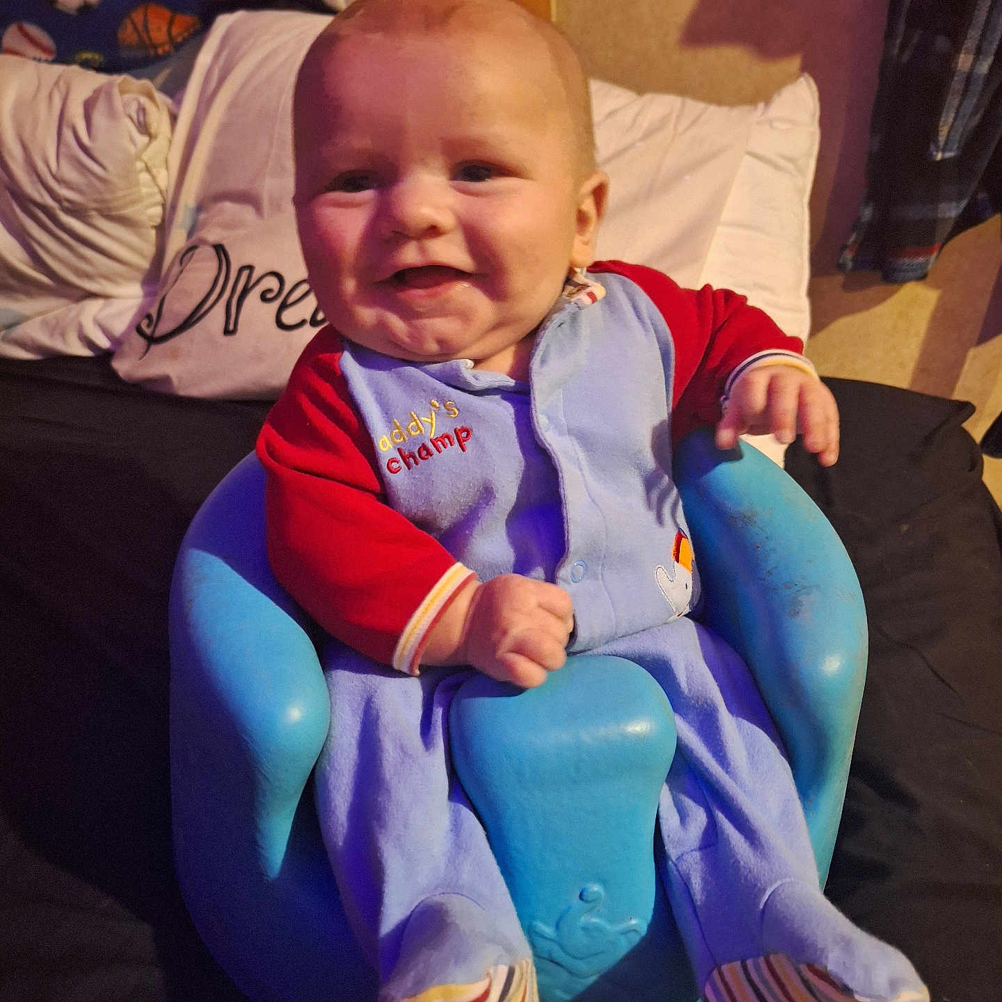 Brayden joined the competition — help win amazing prizes! baby, smiling, blue_baby_chair, red_onesie, cozy_clothing, pillow, blanket, indoor, child, cute, happy, seated, face, infant, footwear, striped_socks, soft_lighting, portrait, newborn, home