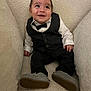 baby, child, tuxedo, bow_tie, suit, smiling, happy, seated, indoor, cushion, plush, shoes, footwear, portrait, cute, small, young, infant, person, clothing