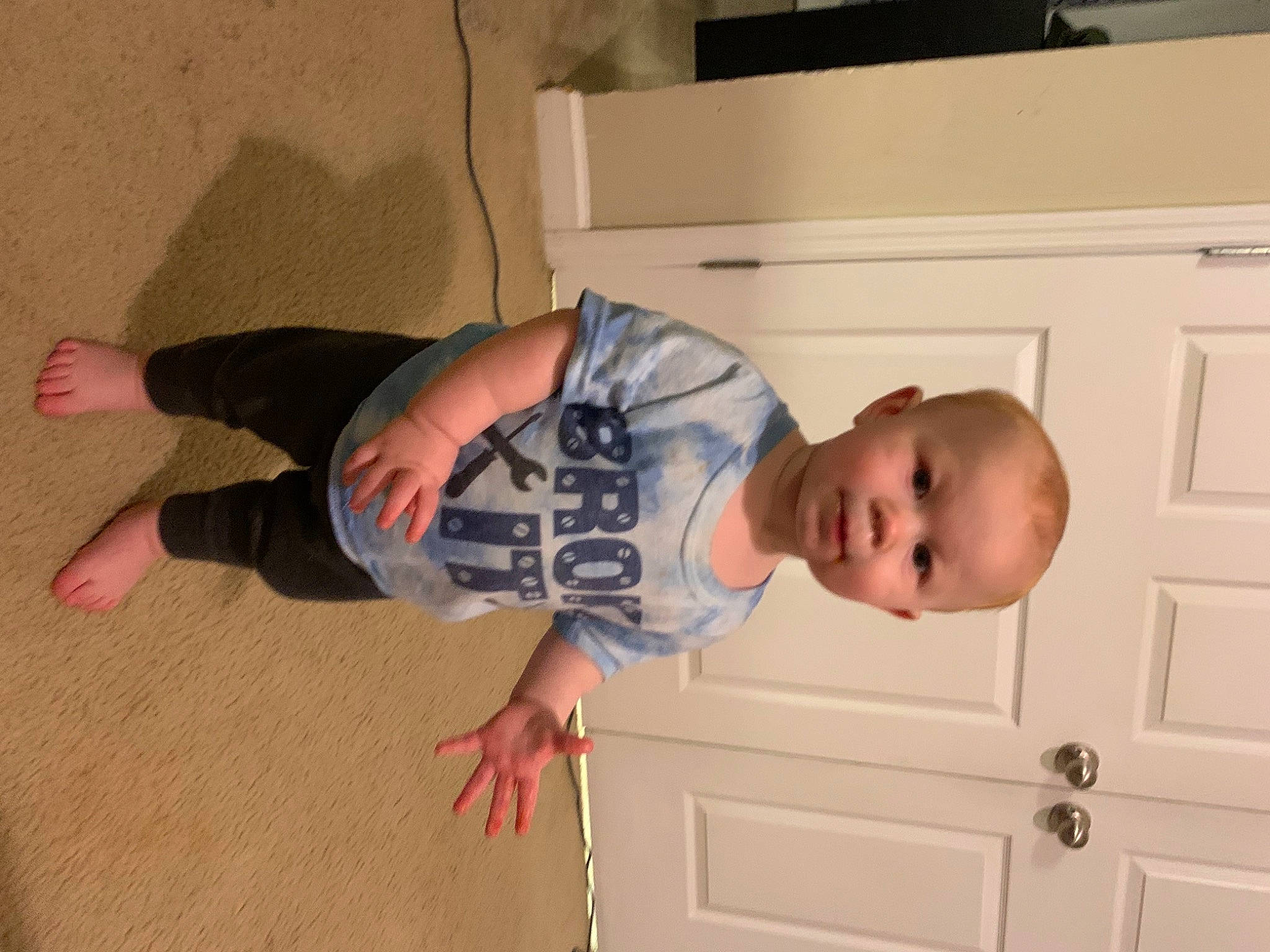 Lucas is registered to the contest to win money with this photo: baby, baby_toddler_clothing, child, comfort, door, elbow, eye, floor, flooring, fun, hardwood, leg, person, room, sleeve, smile, t_shirt, thumb, toddler, wood