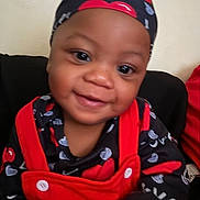 Donavyn is registered to the contest to win money with this photo: baby, child, smiling, red_clothing, black_clothing, headwear, indoor, portrait, cute, face, happy, young_child, infant, love_pattern, fabric, button, person, closeup, seated, warmth