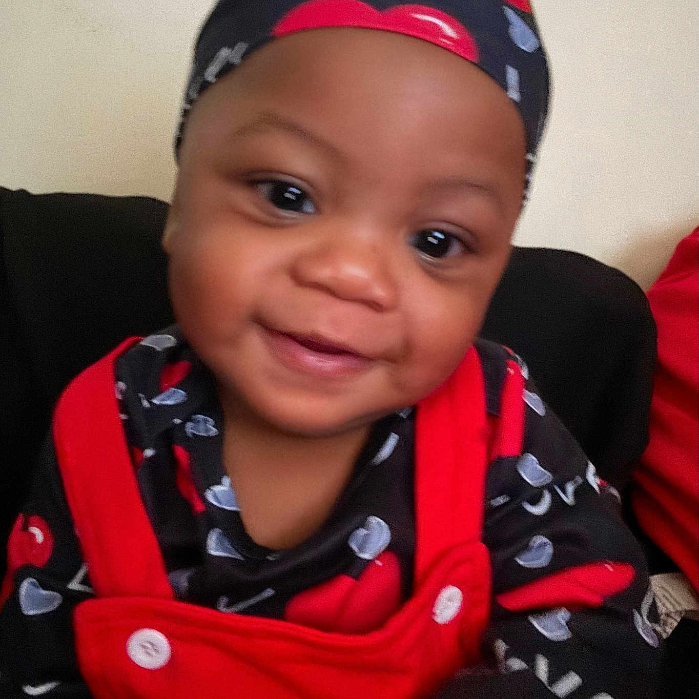 Donavyn is registered to the contest to win money with this photo: baby, black_clothing, button, child, closeup, cute, fabric, face, happy, headwear, indoor, infant, love_pattern, person, portrait, red_clothing, seated, smiling, warmth, young_child