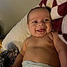 baby, smiling, diaper, blanket, lying_down, chubby_cheeks, happy, infant, cute, skin, indoors, soft_texture, patterned_blanket, face, person, child, young, relaxed, expression, comfort