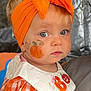 toddler, child, face_paint, orange_bow, headband, pumpkin, fall, costume, bib, orange_checkered, clothing, portrait, cute, serious, indoor, person, baby, fashion, headwear, holiday