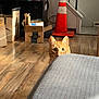 cat, orange_tabby, peeking, couch, wooden_floor, cardboard_boxes, indoor, curious, pet, animal, traffic_cone, furniture, living_room, floor, box, domestic_cat, eyes, alert, home, cozy