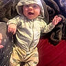 baby, child, infant, portrait, smiling, happy, bucket_hat, hooded_jacket, camouflage, jumpsuit, sitting, lying_down, waving, blanket, cozy, indoor, close_up, face, hands, family