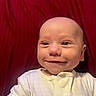 Zachary joined the competition — help win amazing prizes! baby, infant, child, smiling, face, portrait, close_up, indoor, red_background, white_clothing, onesie, sitting, looking_at_camera, happy, cute, head, eyes, nose, mouth, photography