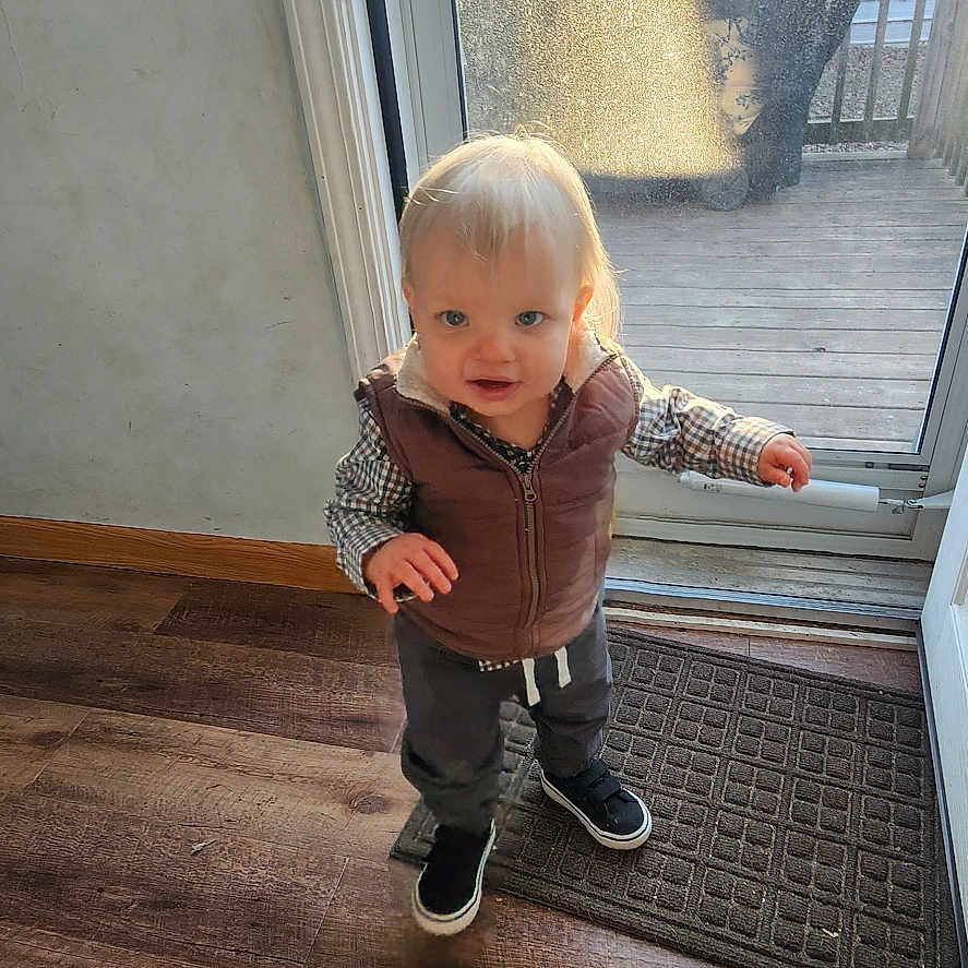 Isaac joined the competition — help win amazing prizes! toddler, child, indoor, wooden_floor, door, glass_door, sunlight, vest, sneakers, curious, standing, person, young_child, light, window, floor_mat, casual_clothing, daylight, home_interior, exploring