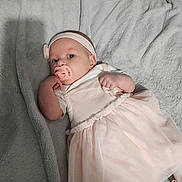 Jasmine is registered to the contest to win money with this photo: baby, infant, pacifier, pink_dress, headband, blanket, towel, bed, soft_texture, lying_down, indoors, cute, child, person, sleepwear, footwear, cozy, resting, portrait, newborn