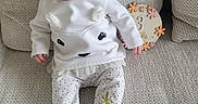 Alyana participe au concours pour gagner de l'argent avec cette photo : baby, infant, child, couch, clothing, white, polka_dot, sitting, cute, milestone, sign, decor, texture, footwear, portrait, indoors, person, soft_light, expression, face