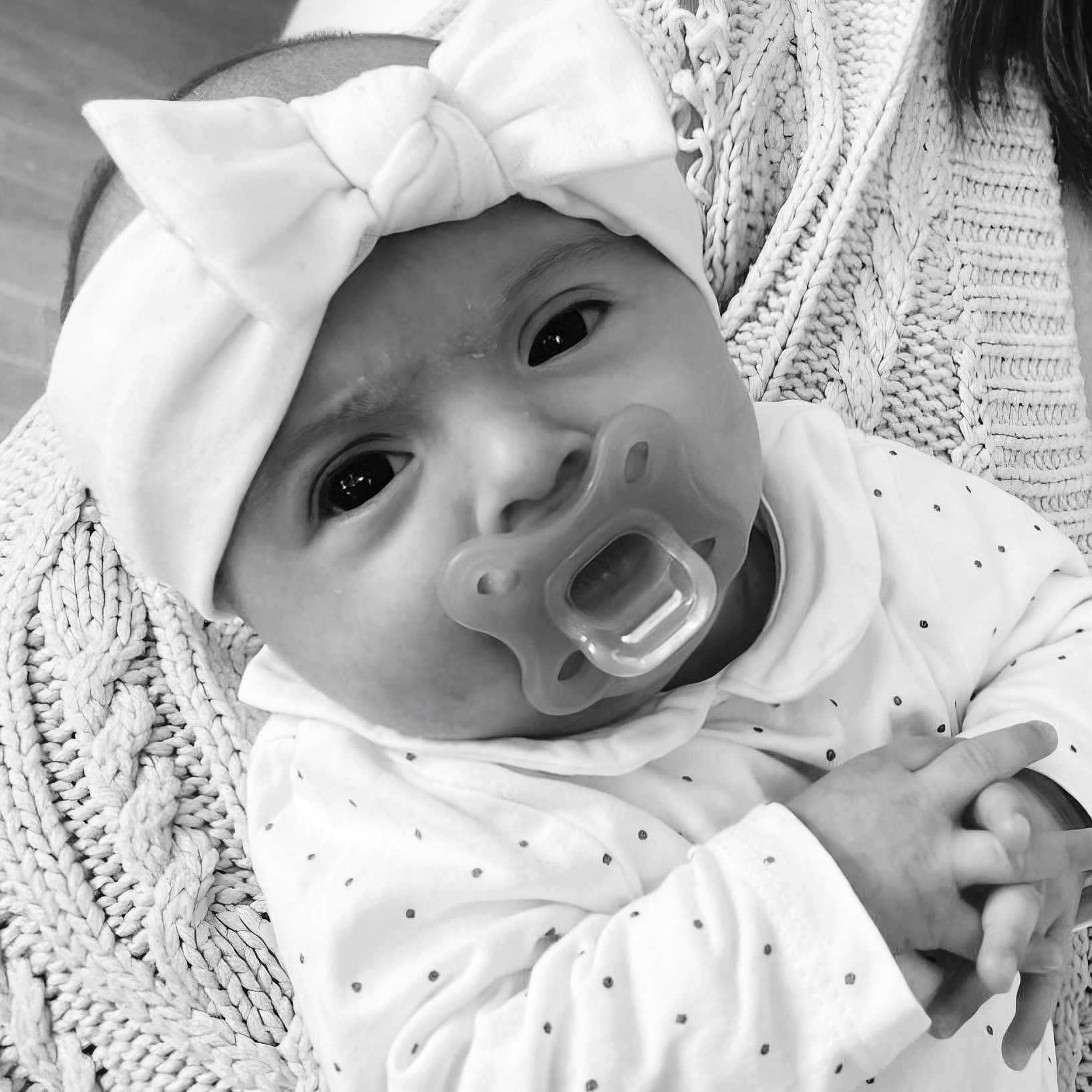 Alyana participe au concours pour gagner de l'argent avec cette photo : baby, infant, headband, bow, pacifier, blanket, knitwear, hands, closeup, portrait, monochrome, black_and_white, cute, child, person, newborn, clothing, face, expression, indoors