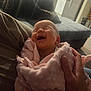 Oaklynn joined the competition — help win amazing prizes! baby, newborn, smiling, blanket, pink, hand, person, indoor, living_room, couch, cozy, soft_texture, happy, infant, wrapped, cute, family, home, warm, gentle