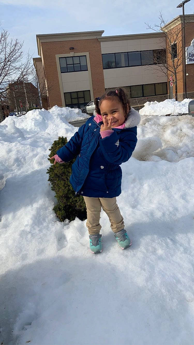 Kylie is registered to the contest to win money with this photo: building, child, electric_blue, freezing, fun, fur, geological_phenomenon, grass, house, joy, leisure, people_in_nature, person, playing_in_the_snow, precipitation, sky, snow, standing, toddler, tree