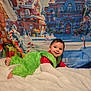 toddler, child, costume, green_fur, holiday, christmas, grinch, blanket, smiling, face, indoor, portrait, festive, background, decor, cute, lying_down, red_shirt, winter, cozy