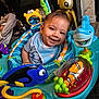 baby, smile, activity_center, toy_fish, toy_shark, toy_turtle, colorful, indoor, child, playtime, happy, infant, clothing, bib, face, seat, furniture, home, resting_baby, floor