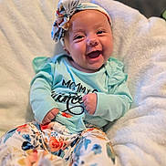 Aurora is registered to the contest to win money with this photo: baby, smiling, headband, floral_pattern, clothing, blanket, infant, happy, cute, portrait, sitting, soft_texture, colorful, person, child, fashion, casual, indoors, face, joy