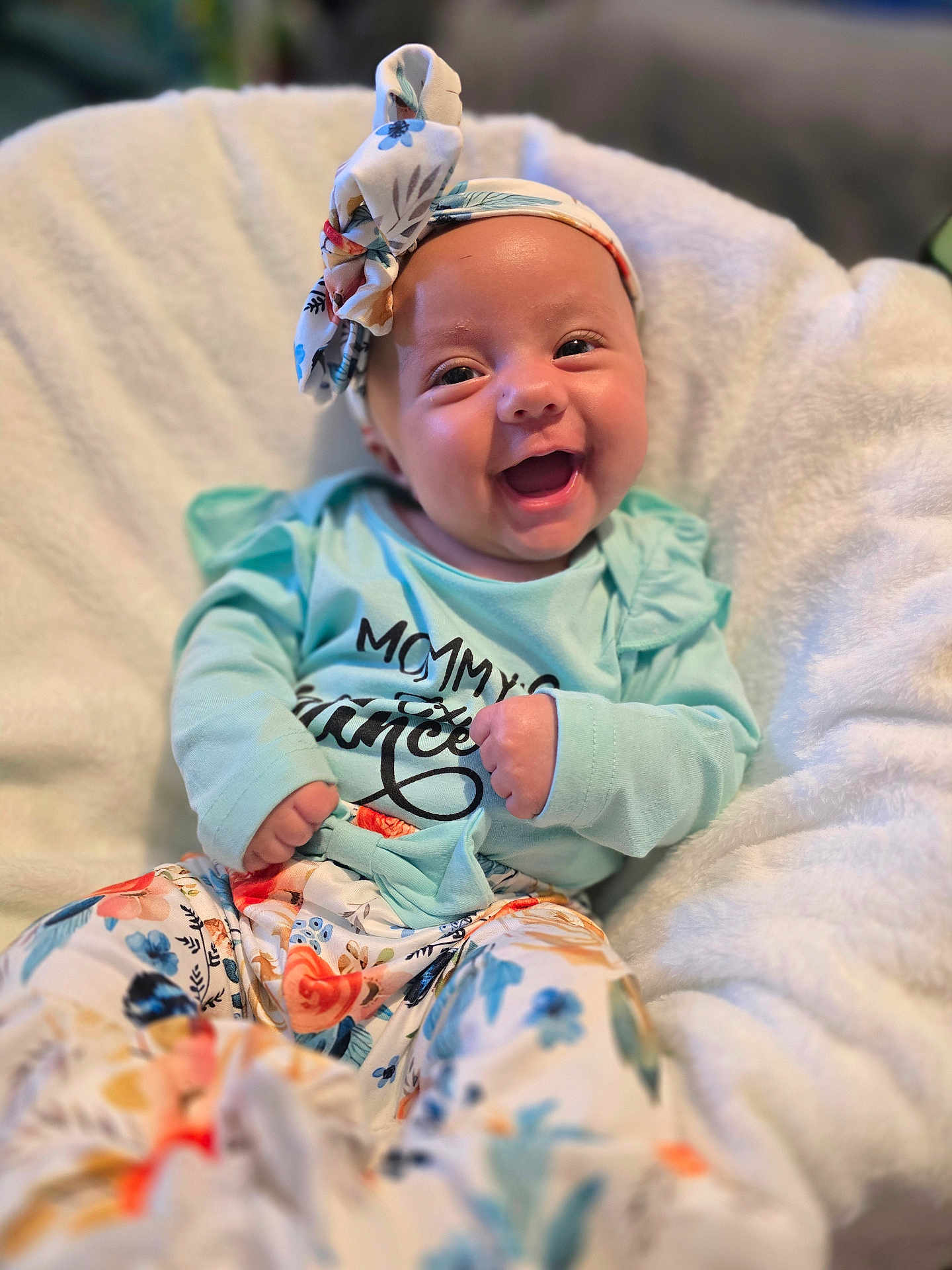 Aurora is registered to the contest to win money with this photo: baby, smiling, headband, floral_pattern, clothing, blanket, infant, happy, cute, portrait, sitting, soft_texture, colorful, person, child, fashion, casual, indoors, face, joy