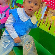 Mia participe au concours pour gagner de l'argent avec cette photo : bench, blonde_hair, blue_sweater, casual_clothing, child, colorful, curious_expression, decor, girl, hair_bow, heart_patch, indoor, pink_clothing, play_area, playroom, ripped_jeans, seated, sneakers, toddler, toys