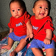 Audrey Dorothea joined the competition — help win amazing prizes! baby, blanket, blue_shorts, child, clothing, cute, face, happy, head, holding_hands, indoor, infant, person, polka_dot, portrait, red_shirt, sitting, smiling, toddler, twin