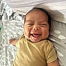 Alexander is registered to the contest to win money with this photo: baby, smiling, tongue_out, infant, lying_down, bed, blanket, cloud_pattern, onesie, cute, happy, child, person, indoors, skin, head, arm, sleepwear, newborn, resting