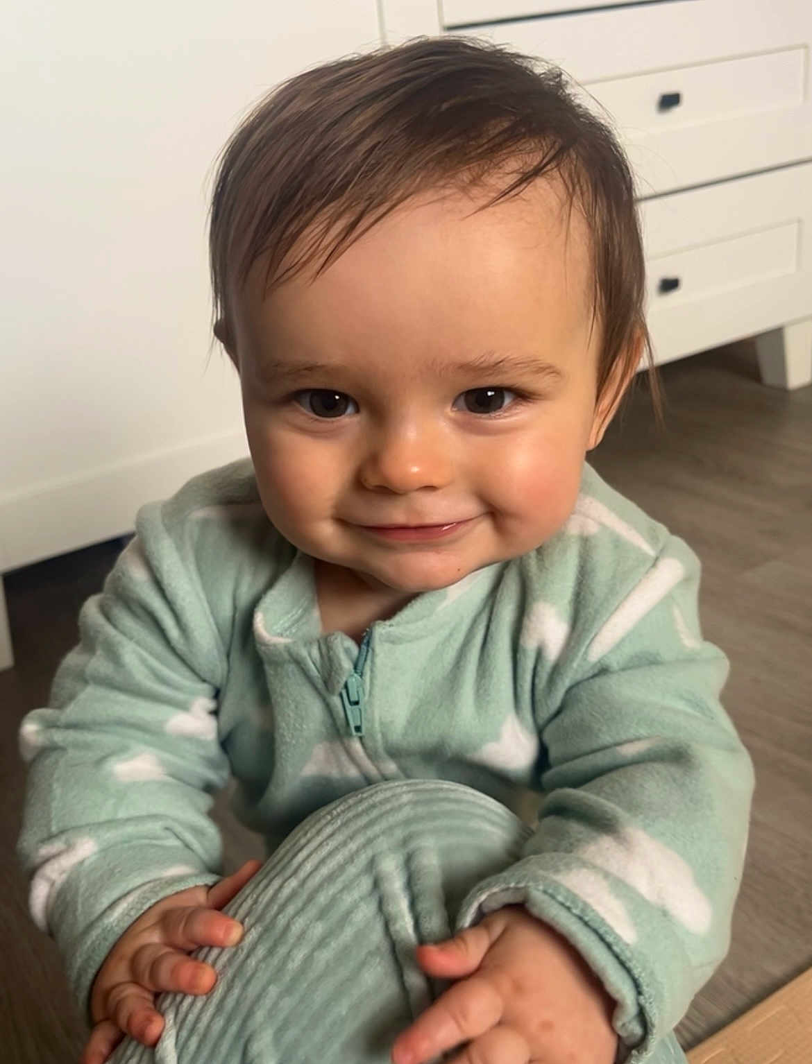 Logan a rejoint le concours — aidez-le/la à gagner de superbes lots ! baby, child, smiling, face, hand, cozy, onesie, mint_green, cloud_pattern, cushion, floor, wooden_floor, drawer, furniture, indoors, portrait, cute, happy, toddler, young_child