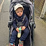 Richie joined the competition — help win amazing prizes! toddler, child, stroller, baby_bottle, cap, sneakers, street, sidewalk, brick_wall, outdoor, casual_clothing, blue_eyes, serious_expression, baby, person, daylight, urban, footwear, hand, seatbelt