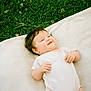 baby, infant, smile, grass, blanket, outdoor, cute, happy, child, person, nature, greenery, lying_down, white_clothing, soft_texture, daylight, head, face, skin, relaxation