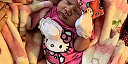 Alora is registered to the contest to win money with this photo: baby, newborn, sleeping, pink, hello_kitty, bow, blanket, mittens, socks, cute, infant, cozy, hand, soft, floral, bed, child, person, rest, comfort