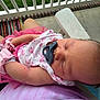 baby, newborn, pacifier, sleeping, pink_clothing, white_clothing, person, lap, outdoor, porch, railing, grass, concrete, rug, tulle_skirt, arm, hand, head, face, peaceful