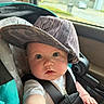 arm, baby, big_eyes, brim, buckle, cap, car_interior, car_seat, chubby_cheeks, close_up, cute, hand, hat, infant, onesie, portrait, seatbelt, star_pattern, sunlight, window