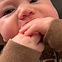 Silas is registered to the contest to win money with this photo: baby, infant, close_up, face, hands, fingers, cheeks, nose, eyes, eyelashes, portrait, skin, onesie, brown_clothing, hand_in_mouth, teething, cute, chubby, indoor, soft_texture