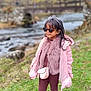 Flora is registered to the contest to win money with this photo: casual, child, crossbody_bag, daylight, fashion, fur_scarf, girl, grass, headband, nature, outdoor, pathway, pink_jacket, river, smiling, sneakers, standing, sunglasses, trees, winter_clothing