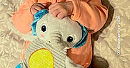 Julietta joined the competition — help win amazing prizes! baby, infant, portrait, lying_down, smiling, bow_headband, orange_outfit, plush_toy, elephant_toy, cushion, patterned_fabric, indoor, close_up, face, hands, feet, cute, child, toy, photography