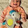 Julietta is registered to the contest to win money with this photo: baby, infant, smiling, happy, portrait, indoors, lying_down, headband, bow, peach_outfit, plush_toy, elephant_toy, cushion, patterned_fabric, blanket, baby_clothing, playtime, close_up, date_text, photograph