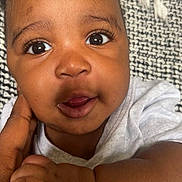 Sefu is registered to the contest to win money with this photo: baby, blanket, child, closeup, clothing, curious, cute, expression, eyes, face, hand, holding, infant, person, portrait, skin, small, texture, toddler, young