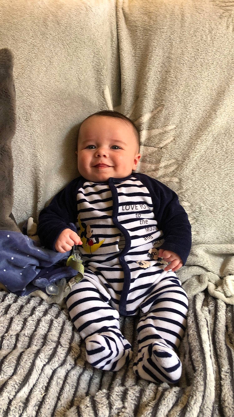 Lucenzo participe au concours pour gagner de l'argent avec cette photo : baby, baby_toddler_clothing, cheek, child, comfort, eye, face, flooring, happy, head, joy, linens, pattern, person, sitting, skin, sleeve, smile, t_shirt, thumb