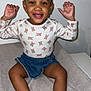 toddler, child, smiling, happy, sitting, denim_skirt, long_sleeve_shirt, animal_print, pigtails, bows, socks, indoor, portrait, cute, baby, person, face, hands, feet, soft_surface