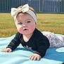 baby, black_shirt, blanket, blue_eyes, bow, casual_clothing, child, cute, expression, floral_pants, grass, headband, infant, laying_down, nature, outdoor, person, snowflake, sunlight, toddler