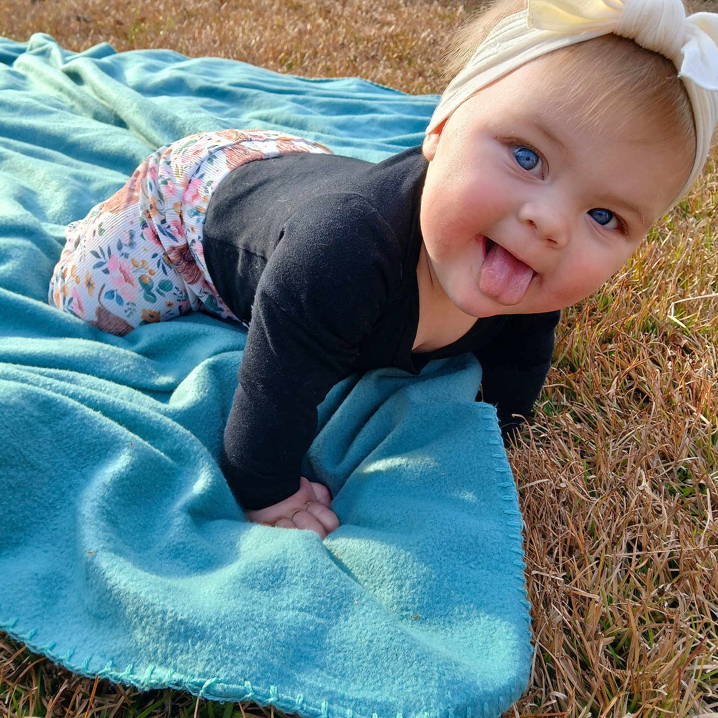 Allison joined the competition — help win amazing prizes! baby, blanket, blue_eyes, bow, car_tire, child, clothing, crawling, cute, grass, happy, headband, infant, nature, outdoor, person, playful, smiling, sunlight, tongue_out