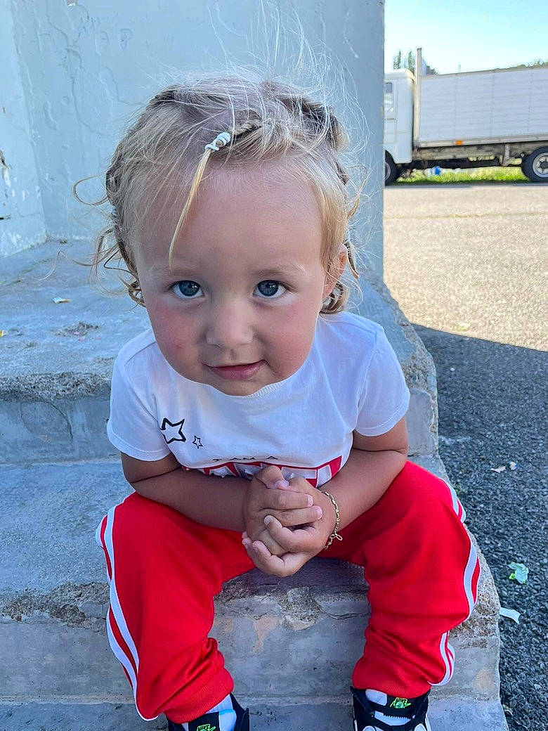 Mike participe au concours pour gagner de l'argent avec cette photo : asphalt, baby, baby_toddler_clothing, child, concrete, cool, electric_blue, fun, grass, happy, person, pink, road_surface, sitting, sky, standing, tire, toddler, truck, wheel