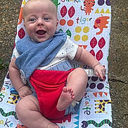 Leif is registered to the contest to win money with this photo: animal_prints, baby, bib, blue_eyes, child, colorful_chair, cute, feet, happy, infant, joyful, legs, outdoor, pattern, playful, portrait, red_harness, seat, smiling, sunlight